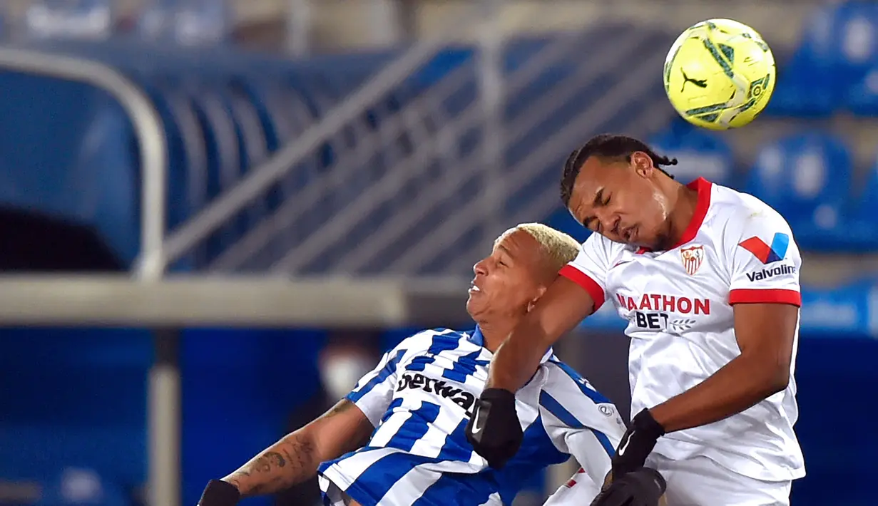 Bek Sevilla, Jules Kounde, berebut bola atas dengan penyerang Alaves, Deyverson Acosta, pada laga lanjutan Liga Spanyol di Stadion Mendizorrotza, Rabu (20/1/2021) dini hari WIB. Sevilla menang 2-1 atas Alaves. (AFP/Ander Gillenea)