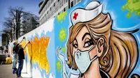 Seniman jalanan Jim Haan membuat mural di pagar konstruksi markas NL Dutch Post NL di Den Haag, Belanda, Jumat (10/4/2020). Seniman jalanan Belanda membuat mural untuk mendukung mereka yang berjuang selama pandemi virus corona COVID-19. (Koen Van WEEL/ANP/AFP)