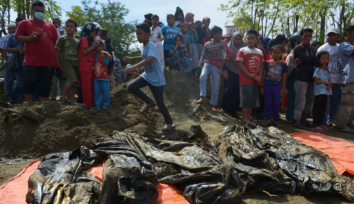 Warga melihat jenazah korban tsunami dan gempa 2004 di Kajhu, Aceh (19/12). Sekitar 30 jenazah korban tsunami Aceh dan gempa bumi ditemukan penduduk desa dekat lokasi konstruksi kompleks perumahan yang baru dibangun. (AFP Photo/Chaideer Mahyuddin)