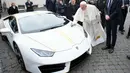 Paus Fransiskus memberikan tanda tangan di kap mesin Lamborghini Huracan di Vatikan, Rabu (15/11). Perusahaan Lamborghini memberi hadiah mobil Lamborghini Huracan berwarna putih untuk Paus Fransiskus. (L'Osservatore Romano/Pool Photo via AP)