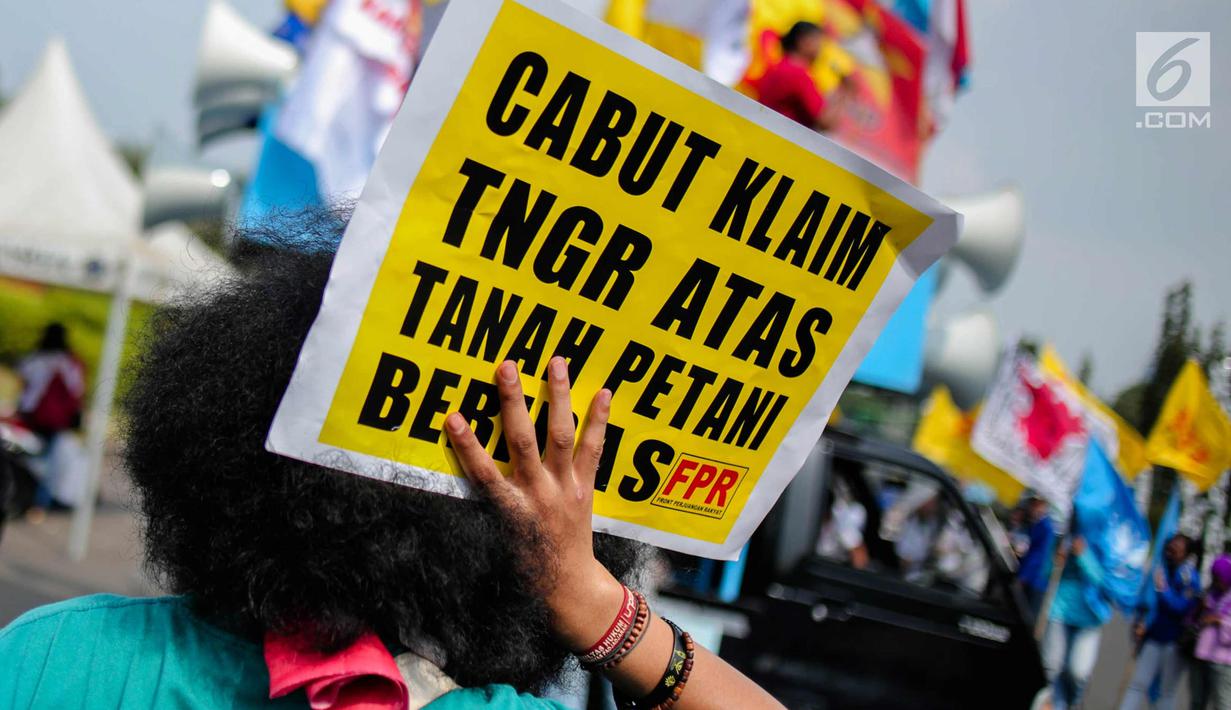 Seorang pengunjuk rasa menunjukkan poster saat menggelar aksi di depan Istana Negara, Jakarta, Senin (25/9). Aksi tersebut sebagai peringatan Hari Tani Nasional (HTN) 2017. (Liputan6.com/Faizal Fanani)