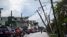 Seorang wanita berjalan melalui jalan setelah Badai Lisa di Belize City, Belize, 3 November 2022. Badai Tropis Lisa menyebabkan banjir dan membuat sebagian negara itu menjadi gelap gulita. (Johan ORDONEZ/AFP)