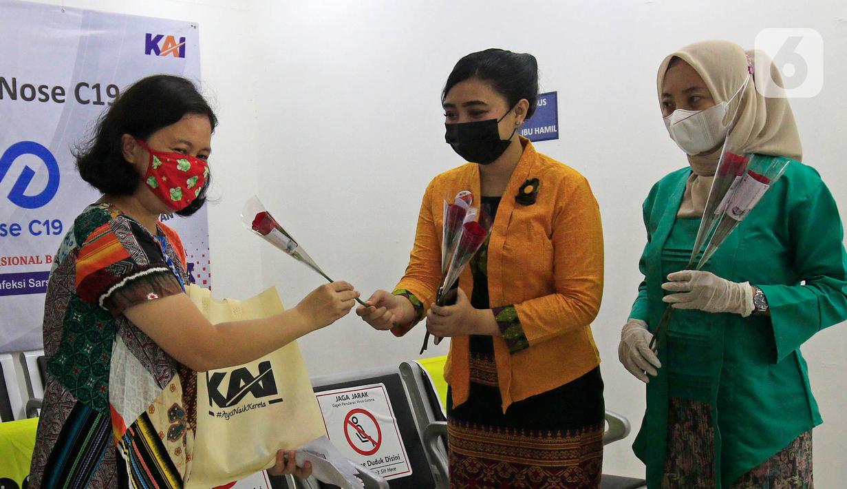 Petugas PT KAI Daop 1 Jakarta berkebaya membagikan bunga kepada penumpang di Stasiun Gambir, Rabu (21/4/2021). PT KAI DAOP 1 memperingati Hari Kartini menginspirasi para penumpang agar semangat berjuang melawan pandemi COVID-19 dengan selalu menerapkan protokol kesehatan. (Liputan6.com/Herman Zakhar