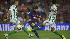 Aksi Lionel Messi (tengah) melepaskan tembakan melewati adangan dua pemain Real Betis pada lanjutan La Liga Spanyol di Camp Nou stadium, Barcelona, (20/8/2017). (AFP/Lluis Gene)