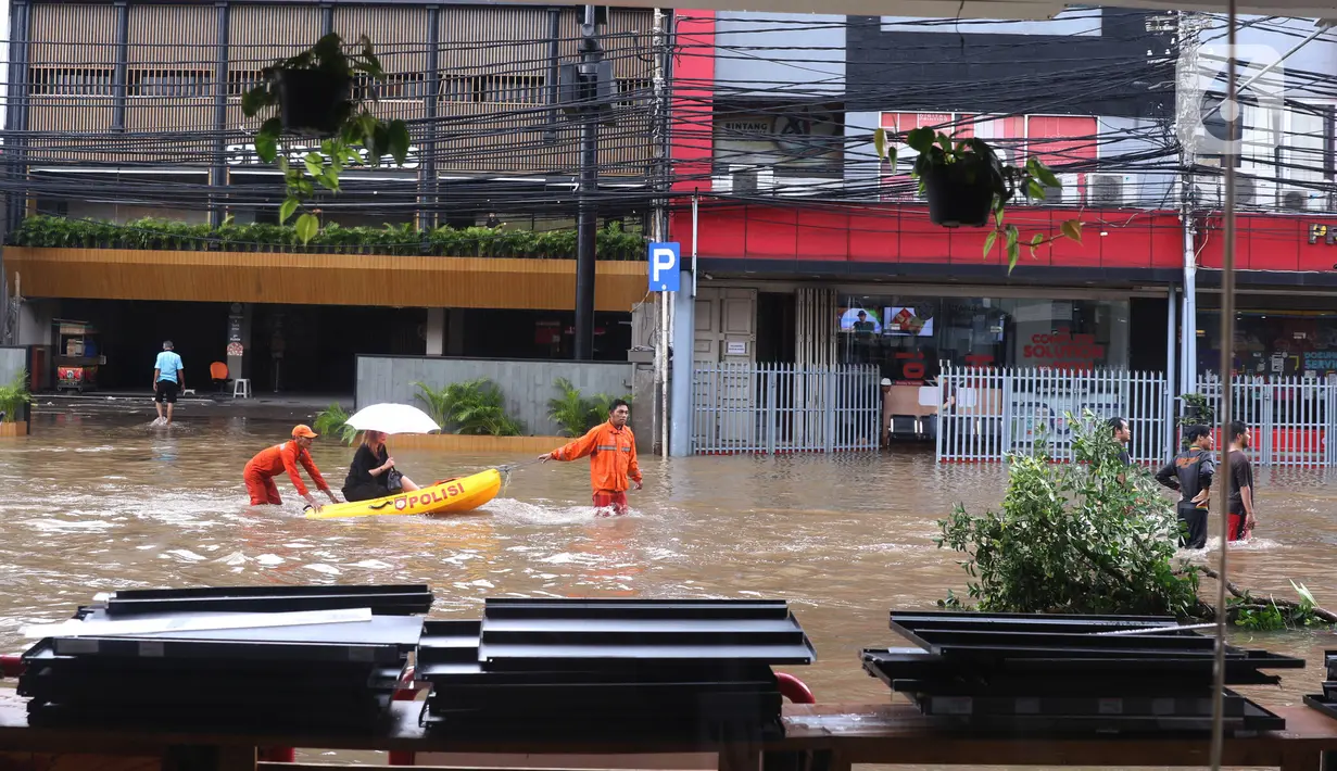 Petugas mengevakuasi warga menggunakan perahu karet saat melintasi banjir yang merendam kawasan Benhil, Jakarta, Selasa (25/2/2020). Hujan yang mengguyur wilayah tersebut membuat air sungai meluap sehingga menyebabkan Banjir setinggi pinggang orang dewasa. (Liputan6.com/Angga Yuniar)