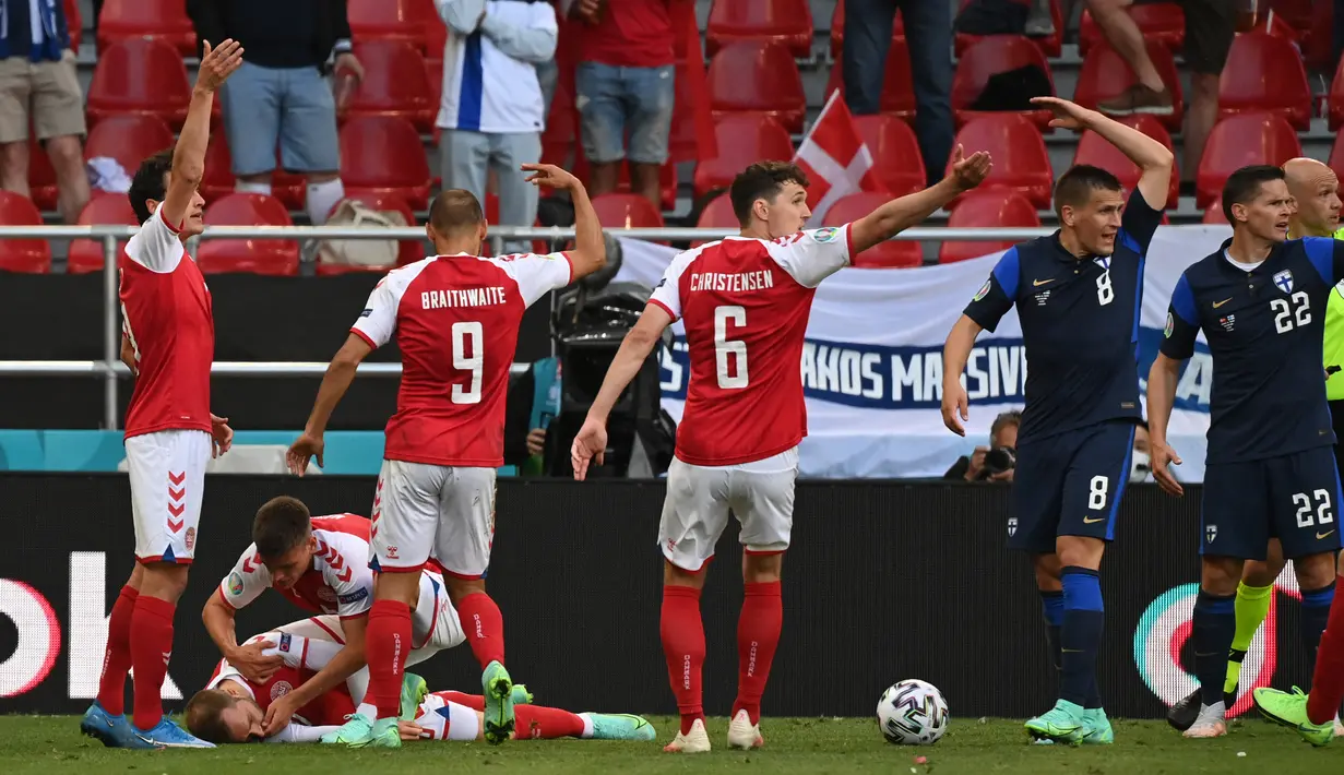 Pemain Denmark membantu rekannya Christian Eriksen yang pingsan sembari memanggil petugas medis pada laga Denmark vs Finlandia di Grup B Euro 2020 di Parken Stadium, Sabtu (12/6/2021). Eriksen tiba-tiba terjatuh dan kehilangan kesadaran saat hendak menyambut lemparan ke dalam. (NACKSTRAND/POOL/AFP)