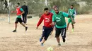 Dua pria berebut bola saat bermain di lapangan tanah sebelum buka puasa selama bulan Ramadhan, di ibu kota Libya, Tripoli (24/4/2021). (AFP/Mahmud Turkia)