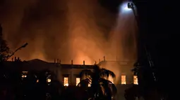 Petugas berusaha memadamkan api saat kebakaran Museum Nasional Brasil yang berusia 200 tahun di Rio de Janeiro, Minggu (2/9). Sejauh ini belum diketahui penyebab kebakaran bangunan bergaya kuno tersebut. (AP/Leo Correa)
