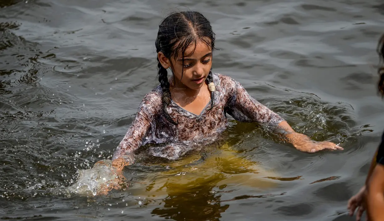 Seorang anak perempuan mendinginkan diri ke perairan Laut Arab saat musim panas di Karachi pada 5 Juli 2020. Warga Pakistan menghabiskan hari yang cerah dengan berenang di tengah pandemi virus corona. (Photo by Rizwan TABASSUM / AFP)