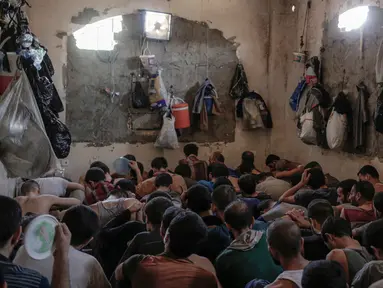 Sejumlah orang yang diduga mantan anggota ISIS ditahan di dalam sel penuh sesak di sebuah penjara selatan kota Mosul, Irak, 18 Juli 2017. Dalam foto itu puluhan pria dijejalkan ke dalam ruangan kecil yang gelap dan tidak berventilasi. (AP/Bram Janssen)