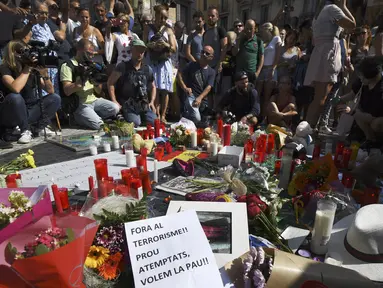 Orang-orang berkumpul sambil menaburkan bunga dan menyalakan lilin untuk memberi penghormatan kepada korban serangan Barcelona, Spanyol (18/8). Sebelum sebuah van menabrak kerumunan dan menawaskan 13 orang. (AFP Photo/Pascal Guyot)