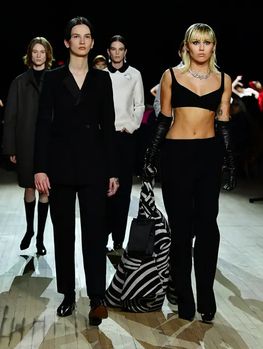 Miley Cyrus (kanan) berjalan di catwalk untuk show Marc Jacobs Fall 2020 selama New York Fashion Week di New York City, Rabu (12/2/2020). Miley Cyrus bergabung dengan sejumlah model di runway termasuk, Gigi Hadid dan adiknya, Bella Hadid serta Kaia Gerber. (Slaven Vlasic/Getty Images/AFP)
