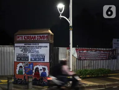 Warga melintas di dekat instalasi peringatan bahaya COVID-19 di kawasan Kemang, Jakarta, Selasa (15/9/2020). Guna mengurangi pola penyebaran COVID-19, Pemda DKI Jakarta kembali menerapkan PSBB dengan membatasi aktivitas warga, perdagangan maupun perkantoran. (Liputan6.com/Helmi Fithriansyah)
