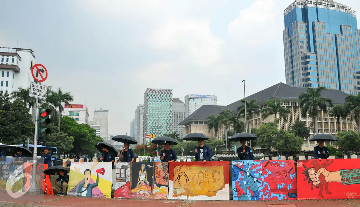 Sejumlah mahasiswa Trisakti menggelar aksi dengan memajang gambar mural bertema kemanusiaan di Bundaran Patung Kuda, Jakarta, Kamis (12/5). Aksi ini bertujuan untuk memperingati tragedi trisakti 12 Mei 98. (Liputan6.com/Yoppy Renato)