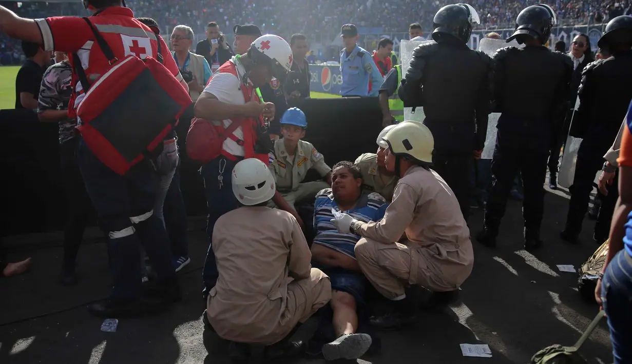 Seorang pria yang terluka mendapat pertolongan dari petugas medis setempat usai terjadi kericuhan dalam pertandingan final sepak bola antara Motagua kontra Progreso di kota Tegucigalpa, Honduras (28/5). (AP Photo/Fernando Antonio)