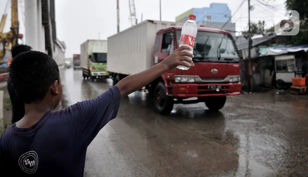 Seorang anak menawarkan jasa membersihkan kaca mobil yang melintas di Jalan Raya Bekasi, Cakung, Jakarta, Selasa (17/3/2020). Dengan sabun yang dikemas dalam botol, anak-anak ini mendapatkan uang seikhlasnya dari pengendara walaupun dapat mengancam keselamatan mereka. (merdeka.com/Iqbal S Nugroho)