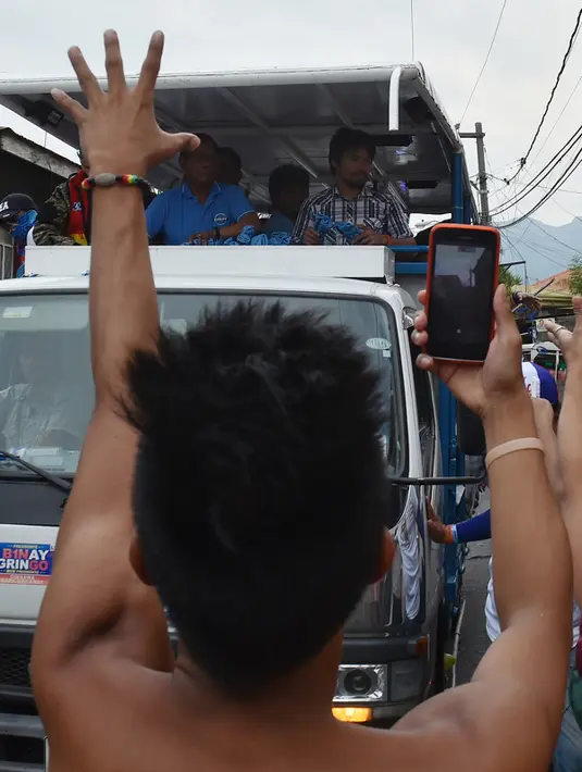 Warga memfoto Manny Pacquiao dengan telpon genggamnya  selama kampanye di kota Calamba, Provinsi Laguna, selatan Manila (28/4). Manny Pacquiao akan ikut  pemilihan menjadi senat Filipina. (AFP PHOTO/TED aljibe)