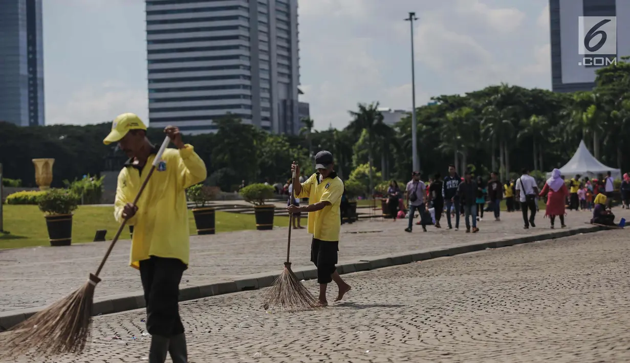 Petugas menyapu membersihkan kawasaan Monas, Jakarta, Senin (1/1). Sebelumnya, kawasan Monas menjadi titik berkumpul warga saat perayaan malam pergantian tahun dan menyisahkan sampah dari pengunjung monas. (Liputan6.com/Faizal Fanani)