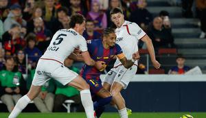 Pemain Barcelona Raphinha beraksi di antara pemain Osasuna Jorge Herrando (kiri) dan Abel Bretones dalam laga Liga Spanyol di Camp Nou, Spanyol, Minggu, 14 Desember 2025. (AP Photo/Joan Monfort)