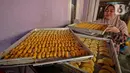 <p>Pembuat kue kering membawa kue pesanan yang telah matang di kawasan Neglasari, Kota Tangerang, Minggu (23/4/2022). Permintaan kue kering di tempat tersebut meningkat saat Ramadhan yang dijual mulai harga Rp50ribu hingga Rp70ribu per toples dan sudah dipasarkan di sekitar Tangerang, Jakarta, hingga Lampung. (Liputan6.com/Angga Yuniar)</p>