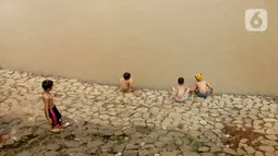 Sejumlah anak bermain di Bantaran sungai Kanal Banjir Barat, Tanah Abang, Jakarta, Sabtu (4/1/2020). Minimnya lahan bermain terpaksa membuat anak-anak harus bermain di bantaran Banjir Kanal Barat meskipun dapat membahayakan keselamatan dirinya. (Liputan6.com/Angga Yuniar)