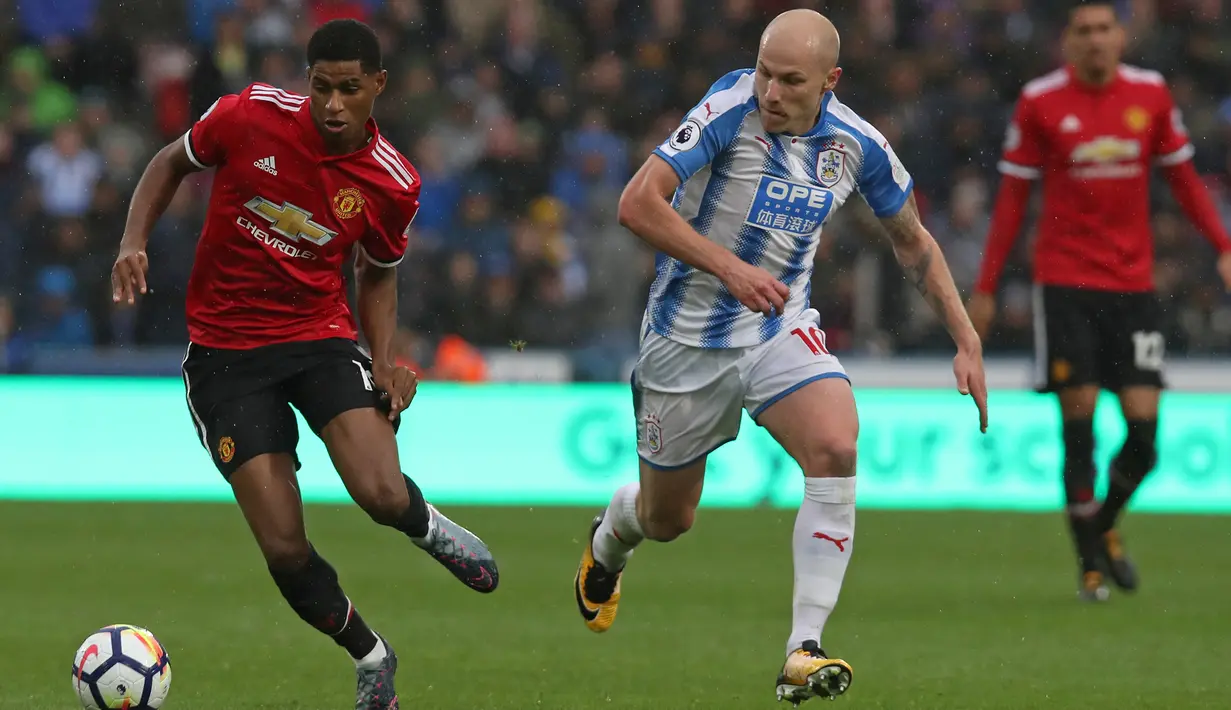Striker Manchester United, Marcus Rashford berusaha membawa bola melewati gelandang Huddersfield, Aaron Mooy saat pertandingan Liga Inggris di stadion John Smith di Huddersfield (21/10). (AFP Photo/Lindsey Parnaby)