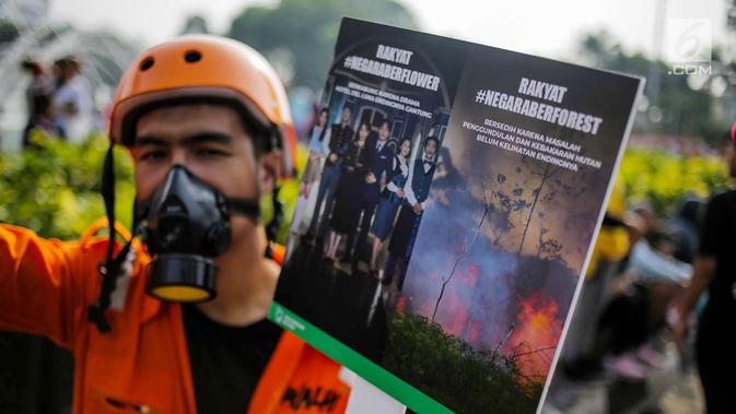 Anggota Walhi Jakarta membawa poster saat menggelar aksi melawan asap dan peduli satwa dalam CFD di Bundaran HI, Jakarta, Minggu (15/9/2019). Walhi menuntut pemerintah segera menyelesaikan permasalahan kebakaran hutan yang berdampak buruk bagi manusia dan lingkungan. (Liputan6.com/Faizal Fanani)