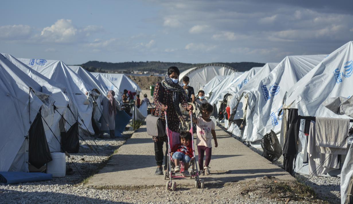 Migran berjalan setelah hujan badai di kamp pengungsi Kara Tepe, di timur laut pulau Lesbos, Aegean, Yunani (14/10/2020).  Sekitar 7.600 pengungsi dan migran telah menetap di kota tenda baru setelah kebakaran berturut-turut pada tanggal 14 September. (AP Photo/Panagiotis Balaskas)