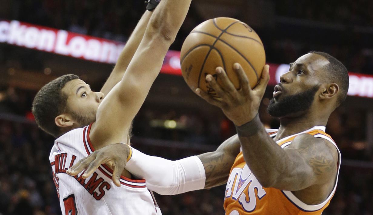 Bintang Cleveland Cavaliers, LeBron James (kanan) melakukan layup melewati hadangan pemain Chicago Bulls, Michael Carter-Williams pada aga NBA basketball game di Quicken Loans Arena, Cleveland. (AP/Tony Dejak)