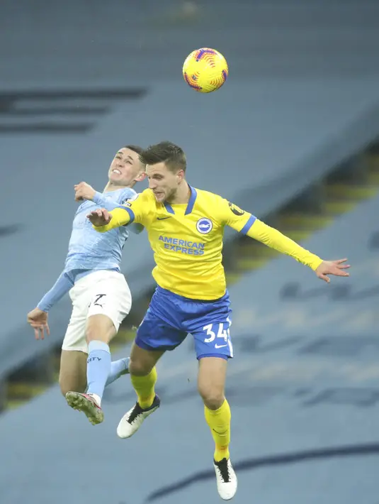 Pemain Manchester City Phil Foden (kiri) berebut bola dengan pemain Brighton and Hove Albion Joel Veltman pada pertandingan Liga Inggris di Etihad Stadium, Manchester, Inggris, Rabu (13/1/2021). Manchester City menang 1.0. (Clive Brunskill /Pool via AP)