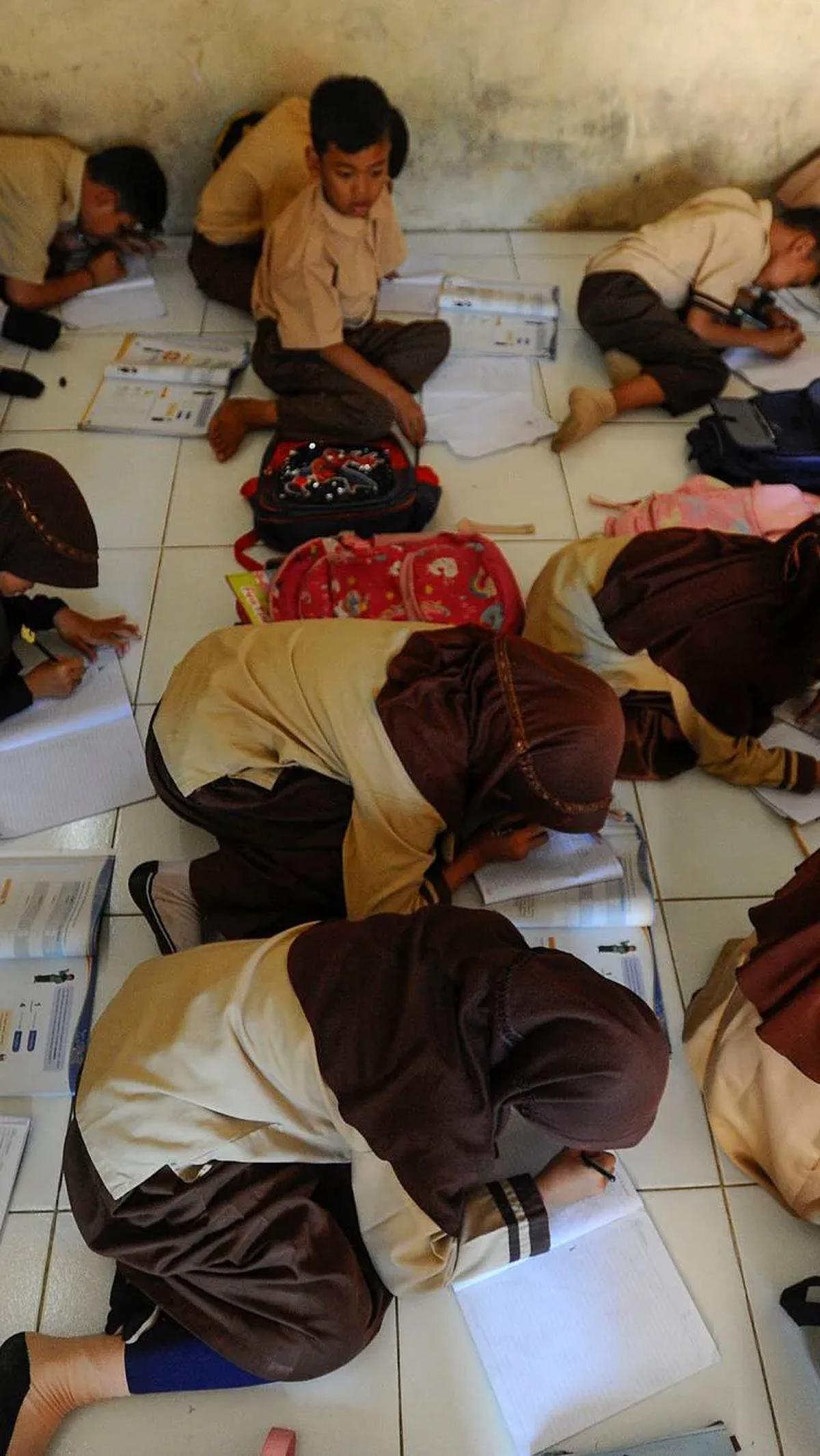 Kegiatan Belajar Mengajar (KBM) dilakukan dengan kondisi tanpa meja dan kursi di sekolah.