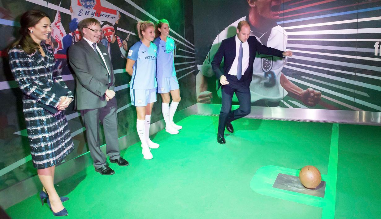 Kate Middleton memperhatikan Pengeran Wiliam beraksi menendang bola pada saat mengunjungi Museum Nasional Sepak Bola di Manchester, Inggris (14/10). Sepak bola merupakan bagian penting dari negara Inggris. (Reuters/Charlotte Graham)