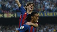 Ronaldinho menggendong Lionel Messi usai memberikan assist untuk gol pertamanya bagi Barcelona. (AFP/Lluis Gene)
