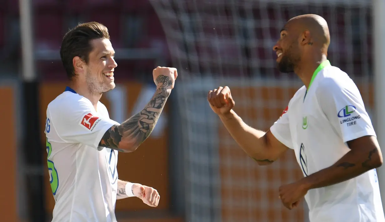 Pemain Wolfsburg Daniel Ginczek dan John Brooks merayakan gol yang dicetak ke gawang FC Augsburg pada laga Bundesliga di Augsburg, Sabtu (16/5/2020). Pandemi COVID-19 membuat pemain melakukan selebrasi jaga jarak. (AFP/Tobias Hase)