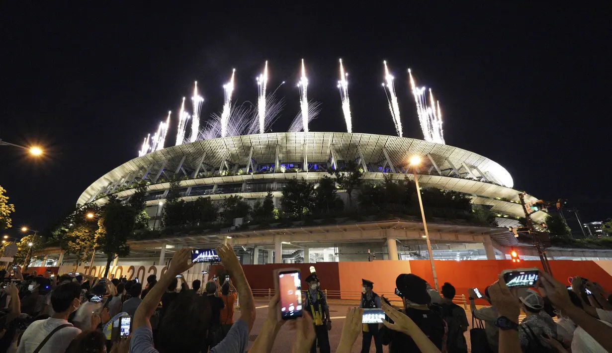Orang-orang berkumpul dekat Stadion Nasional untuk menyaksikan kembang api yang diluncurkan saat upacara penutupan Olimpiade Tokyo 2020 di Tokyo, Jepang, Minggu (8/8/2021). Olimpiade Tokyo 2020 resmi ditutup. (AP Photo/Kantaro Komiya)
