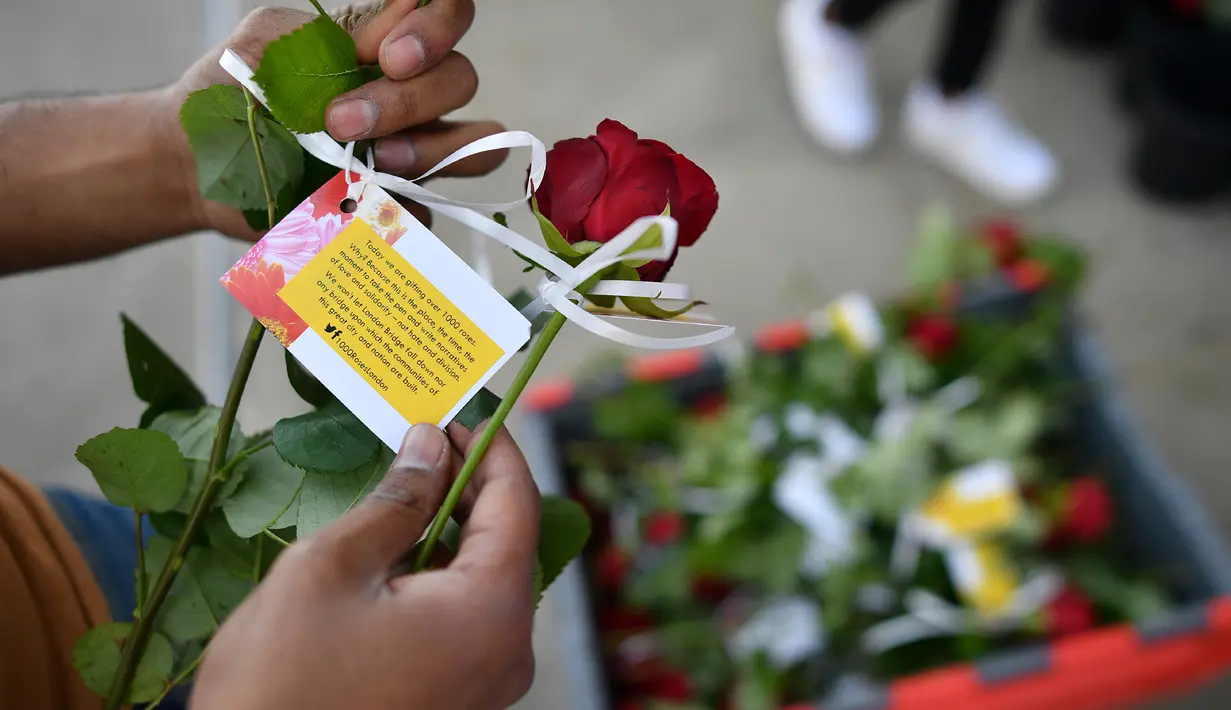 Mawar yang disertai sebuah pesan dibagikan kepada para pejalan kaki di London Bridge, Minggu (11/6). Muslim Inggris membagikan ratusan mawar sebagai bentuk solidaritas menyusul serangan teror London yang terjadi pekan lalu. (Ben STANSALL/AFP)