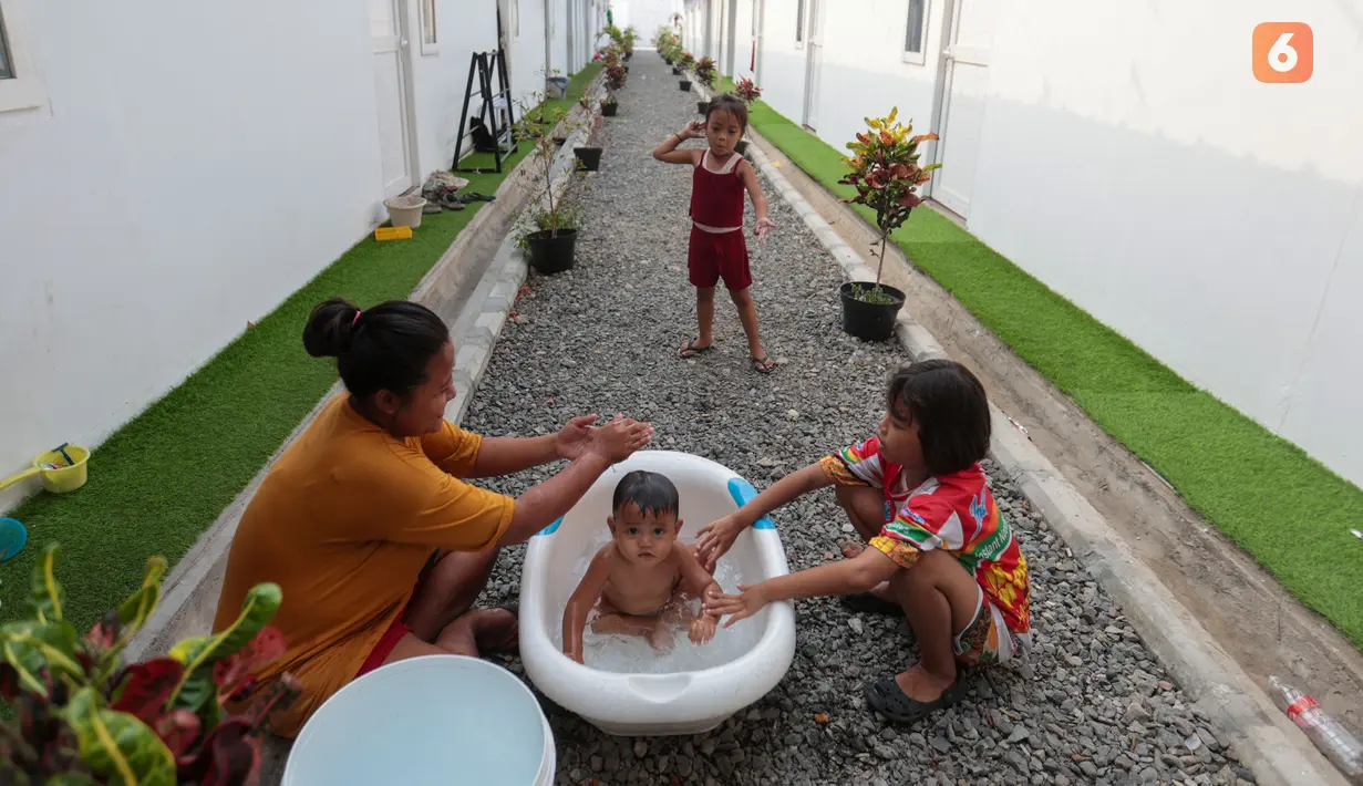 Seorang ibu memandikan anaknya di lingkungan Hunian Sementara (Huntara) di Jalan Kramat Raya, Jakarta, Selasa (8/9/2026). Warga mulai menempati hunian tersebut sejak akhir Juni 2026 setelah sebelumnya tinggal di sekitar bantaran rel kawasan Senen. (KLY/Budy Santoso)