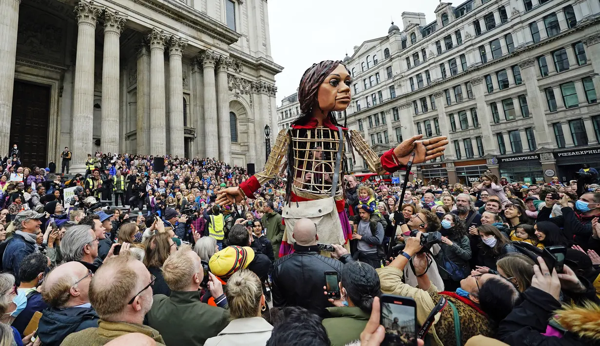 Boneka raksasa Little Amal disambut ratusan warga saat tiba di kota London, Inggris, Sabtu (23/10/2021). Little Amal merupakan boneka berukuran raksasa yang menjadi simbol pengungsi anak dari Suriah.(Aaron Chown/PA via AP)