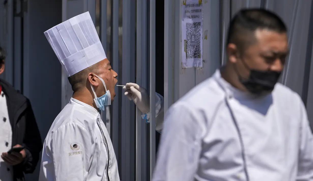 Seorang koki restoran mengambil sampel swab tenggorokan di tempat pengujian virus corona di Beijing, Minggu (3/4/2022). Kasus COVID-19 di kota terbesar di China, Shanghai, masih meningkat saat jutaan orang tetap terisolasi di rumah di bawah lockdown besar-besaran. (AP Photo/Andy Wong)
