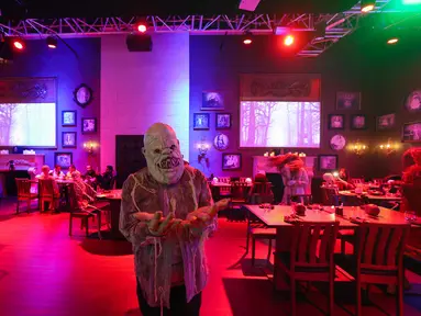 Aktor berkostum zombie memeriahkan suasana di restoran "Shadows" bertema horor di kota hiburan Boulevard, Riyadh, Arab Saudi, 19 Januari 2022. Restoran tersebut menawarkan pengalaman unik kepada pelanggan dari hidangan dengan tengkorak dan darah ditemani zombie serta vampir. (Fayez Nureldine/AFP)