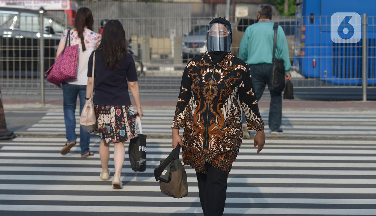 Seorang wanita yang mengenakan baju batik berjalan di kawasan Thamrin Sudirman, Jakarta, Jumat (2/10/2020). Pada Hari Batik Nasional yang berlangsung di tengah pandemi COVID-19, sebagian masyarakat terlihat mengenakan baju dan masker dengan motif batik. (merdeka.com/Imam Buhori)