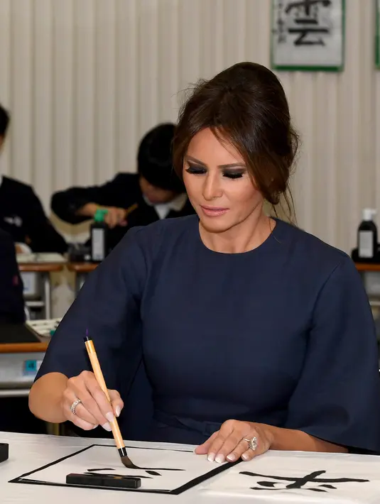 Ibu Negara AS Melania Trump menulis kanji saat menghadiri kelas kaligrafi di sekolah dasar Kyobashi Tsukiji, Tokyo (6/11). Melania Trump dan Akie Abe menulis huruf kanji yang berarti "Damai". (AFP Photo/Pool/Toshifumi Kitamura)