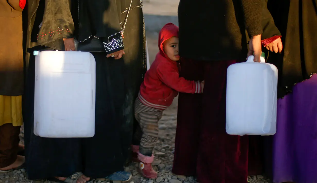 Seorang bocah ikut mengantre bahan bakar yang akan digunakan untuk memasak dan penerangan di Khazer Camp, Irak, Kamis (24/11). (REUTERS / Mohammed Salem)