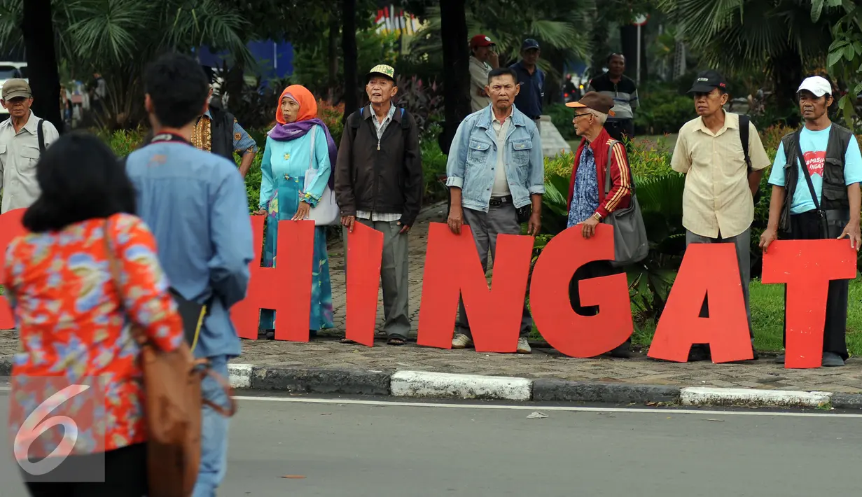 Warga melintas di depan aksi #masihingat yang dilakukan sejumlah keluarga korban kekerasan di Taman Gunung Agung Jakarta, Rabu (29/6). Aksi ini mengingatkan masih banyak kasus pelanggaran HAM yang belum tuntas. (Liputan6.com/Helmi Fithriansyah)