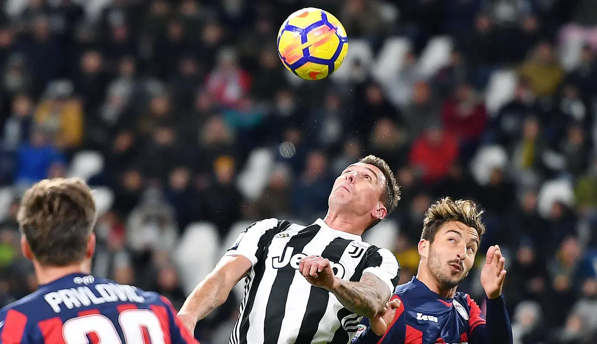Pemain Juventus, Mario Mandzuki melompat untuk merebut bola dari pemain Crotone pada laga pekan ke-14 Liga Italia Seri A di Allianz Stadium, Senin (27/11). Juventus harus bersusah payah bisa menundukkan Crotone, 3-0. (Alessandro Di Marco/ANSA via AP)