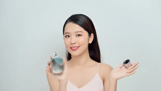 Seorang perempuan sedang memegang sebuah botol parfum (Foto Dok: Freepik/makistock)