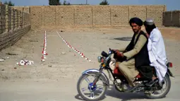 Warga berkendara melewati ladang ranjau di desa Nad-e-Ali, provinsi Helmand pada 9 November 2021. Sekitar 41.000 warga sipil Afghanistan terbunuh atau terluka oleh ranjau darat dan persenjataan yang tidak meledak sejak 1988, menurut Layanan Pekerjaan Ranjau PBB (UNMAS). (Javed TANVEER/AFP)