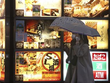 Dua wanita mengenakan masker untuk membantu melindungi diri dari penyebaran virus corona berjalan di sepanjang jalan yang dipenuhi bar dan restoran di Tokyo, Selasa (22/3/2022). Langkah-langkah pra-darurat untuk mencegah wabah Covid-19 telah dicabut. (AP Photo/Koji Sasahara)