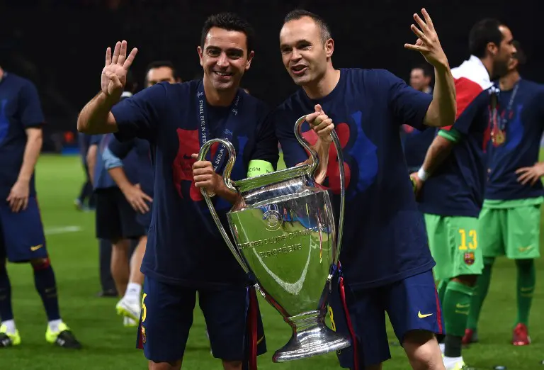 Dua pemain Barcelona Xavi Hernandez dan Andres Iniesta berpose dengan trofi Liga Champions. Barcelona rebut gelar 2015 seusai kalahkan Juventus di final. (AFP/Patrik Stollarz)