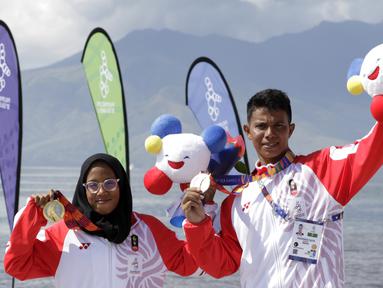 Atlet modern pentathlon, Muhammad Taufik dan Dea Salsabila, berpose usai meraih medali pada nomor beach triathle individual SEA Games 2019 di Subic, Jumat (6/12). Taufik meraih perunggu dan Dea meraih emas. (Bola.com/M Iqbal Ichsan)